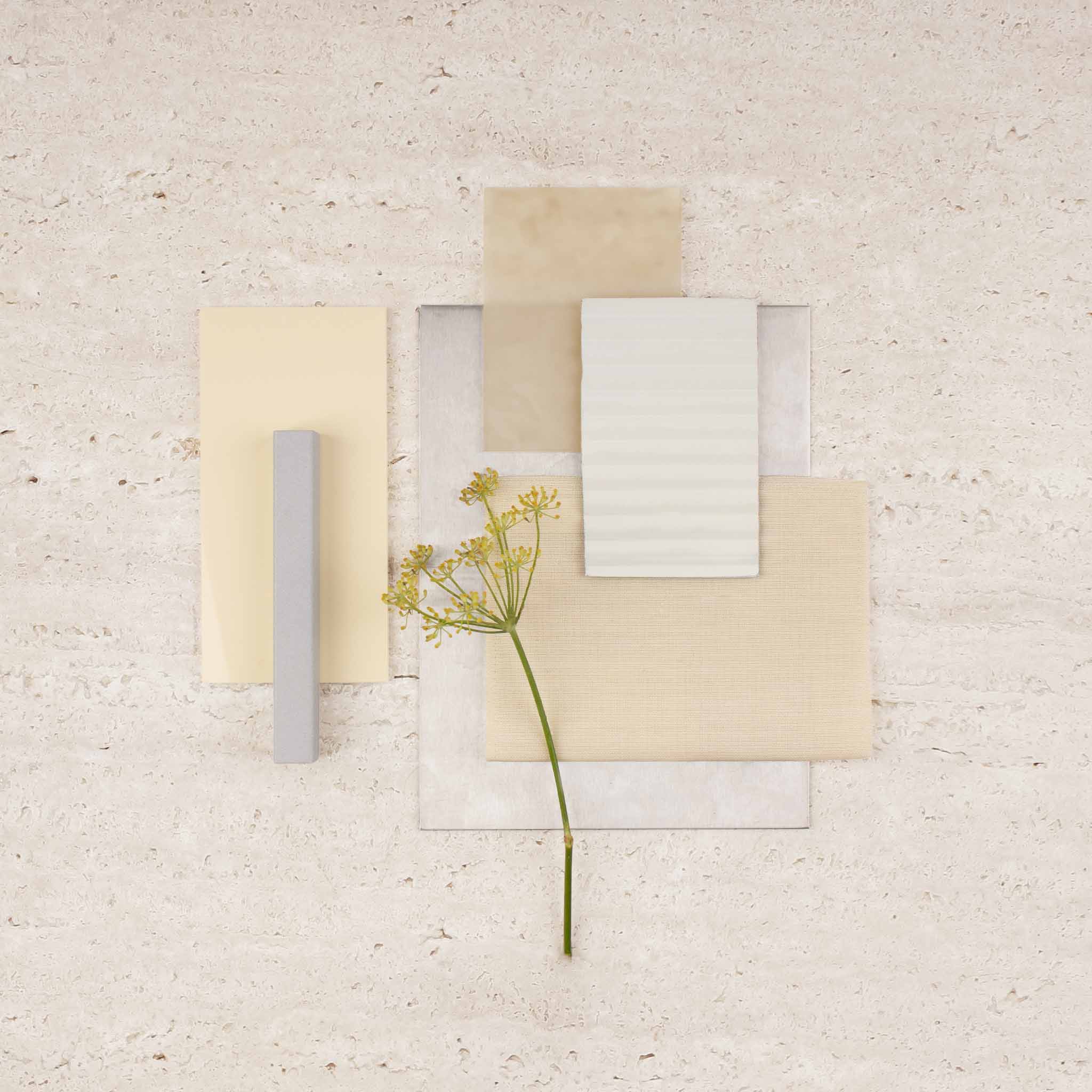 Branche de fleurs jaunes s&eacute;ch&eacute;es pos&eacute;e sur plusieurs morceaux de papier rectangulaires beige et gris sur une surface claire.