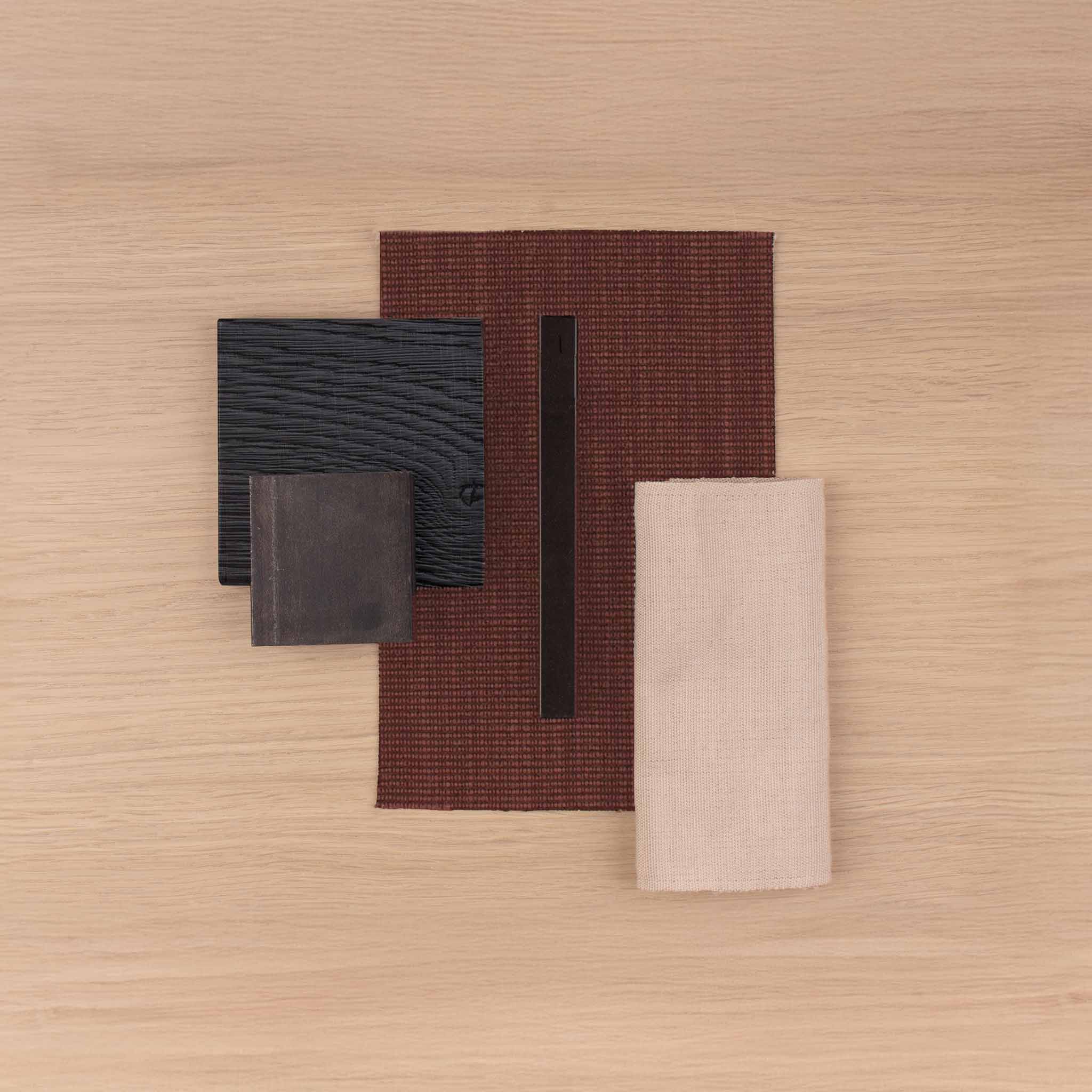 Quatre &eacute;chantillons rectangulaires de mat&eacute;riaux en tons marron, noir et beige sur une surface en bois clair.